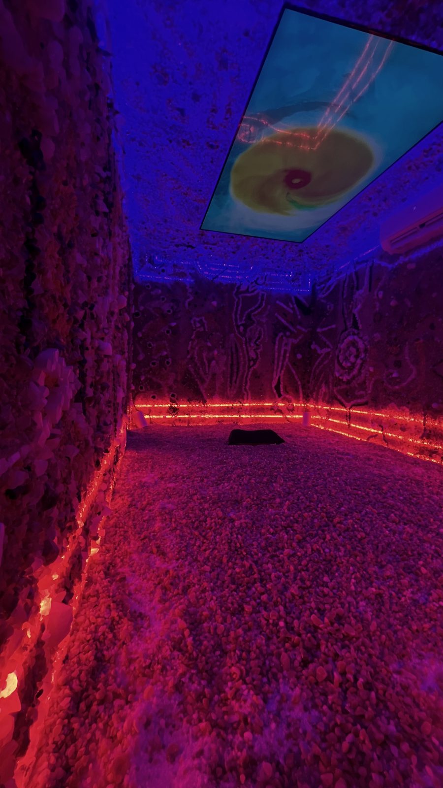 A Crystal Chamber with crystal-covered walls and a salt floor, lit in warm red